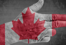 Il Canada valuta la proibizione delle armi Mano che fa gesto della pistola con bandiera del Canada sul dorso: Ottawa valuta la proibizione delle armi