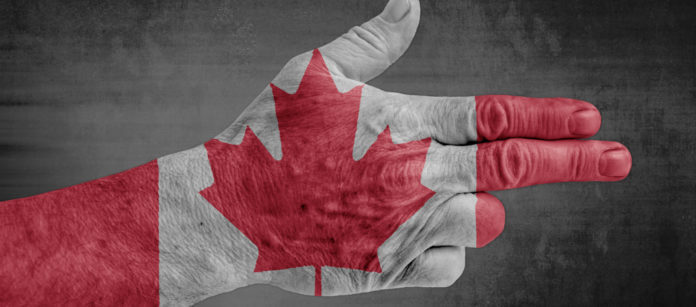 Mano che fa gesto della pistola con bandiera del Canada sul dorso: Ottawa valuta la proibizione delle armi