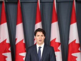 Il governo canadese fa sul serio sul divieto di detenzione di armi d’assalto e pistole Il primo ministro canadese Justin Trudeau dietro a un podio davanti a nove bandiere canadesi. Si va verso il divieto di detenzione di armi d'assalto e di pistole.