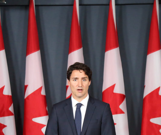 Il governo canadese fa sul serio sul divieto di detenzione di armi d’assalto e pistole Il primo ministro canadese Justin Trudeau dietro a un podio davanti a nove bandiere canadesi. Si va verso il divieto di detenzione di armi d'assalto e di pistole.