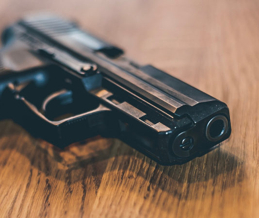 Recepimento della Direttiva armi: dalla Camera parere favorevole con osservazioni pistola in uso alla polizia tedesca su tavolo di legno