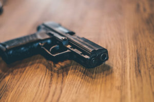 pistola in uso alla polizia tedesca su tavolo di legno: recepimento della Direttiva armi