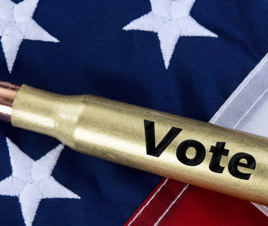 Lo studio dell’Università del Kansas sulla partecipazione politica dei proprietari di armi munizione con scritta "vote" su bandiera americana: studio sulla partecipazione politica dei proprietari di armi