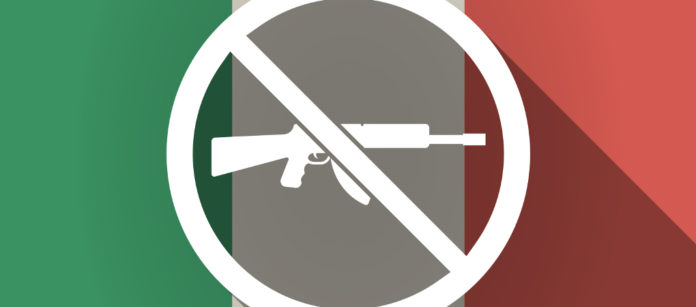 fucile d'assalto barrato su fondo di bandiera italiana: Auda contro il recepimento della nuova Direttiva armi