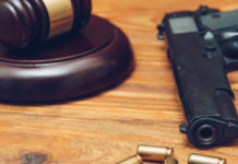 Botta e risposta Salvini – Anm sulla riforma della legittima difesa martello del giudice con pistola e quatto proiettili su tavolo di legno: botta e risposta Salvini - Anm sulla riforma della legittima difesa