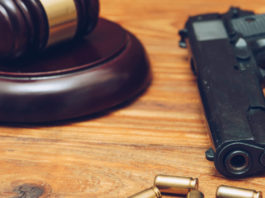 Botta e risposta Salvini – Anm sulla riforma della legittima difesa martello del giudice con pistola e quatto proiettili su tavolo di legno: botta e risposta Salvini - Anm sulla riforma della legittima difesa