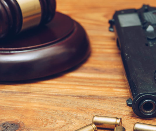 Botta e risposta Salvini – Anm sulla riforma della legittima difesa martello del giudice con pistola e quatto proiettili su tavolo di legno: botta e risposta Salvini - Anm sulla riforma della legittima difesa