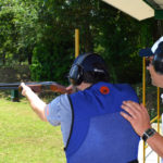 un tiratore spara, assistito a un istruttore della Compak Club Shooting Academy