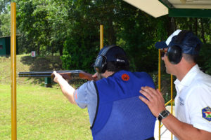 un tiratore spara, assistito a un istruttore della Compak Club Shooting Academy