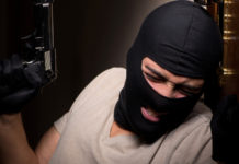 Riforma della legittima difesa: ecco gli emendamenti al testo base rapinatore appoggiato a una porta con pistola e passamontagna