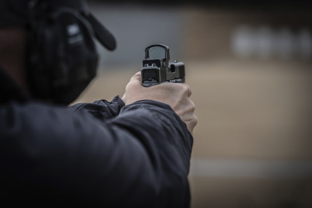 uomo visto da dietro prende la mira con la pistola glock g45 mos