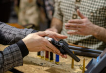 Ora la riapertura delle armerie: la richiesta di Anpam e Assoarmieri per la fase 2 riapertura delle armerie: armiere mostra pistola a cliente