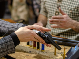 Ora la riapertura delle armerie: la richiesta di Anpam e Assoarmieri per la fase 2 riapertura delle armerie: armiere mostra pistola a cliente