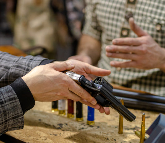 Ora la riapertura delle armerie: la richiesta di Anpam e Assoarmieri per la fase 2 riapertura delle armerie: armiere mostra pistola a cliente