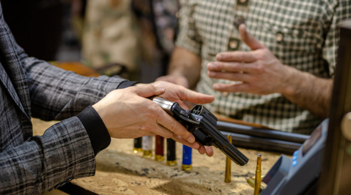 riapertura delle armerie: armiere mostra pistola a cliente