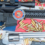 Slitta ancora la data della convention Nra data della convention Nra: armi e proiettili su bandiera americana con sticker Nra