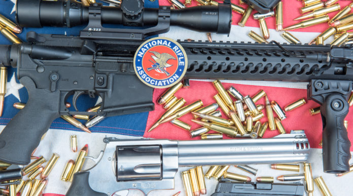 data della convention Nra: armi e proiettili su bandiera americana con sticker Nra