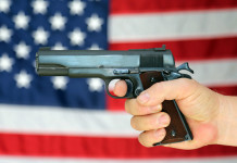 Background check richiesti a febbraio: segni da interpretare background check: pistola impugnata davanti a bandiera americana