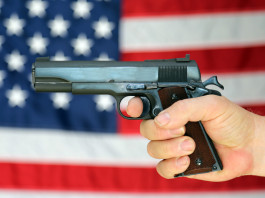 Background check richiesti a febbraio: segni da interpretare background check: pistola impugnata davanti a bandiera americana