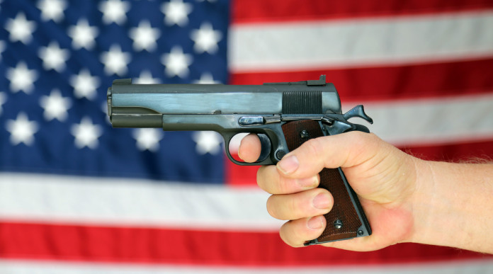 background check: pistola impugnata davanti a bandiera americana