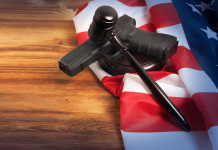 Età minima per acquistare le armi negli Stati Uniti: la sentenza Età minima per acquistare le armi negli Stati Uniti: pistola con bandiera americana e martello del giudice