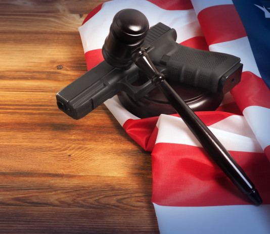 Età minima per acquistare le armi negli Stati Uniti: la sentenza Età minima per acquistare le armi negli Stati Uniti: pistola con bandiera americana e martello del giudice