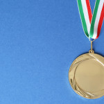 Campionati italiani di tiro a segno: ecco i vincitori Campionati italiani di tiro a segno: medaglia d'oro con bandiera italiana, fondo azzurro