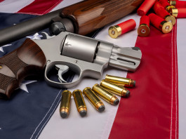Background check richiesti in America, il dato finale del 2021 Background check richiesti in America: revolver e fucile con munizioni su bandiera americana