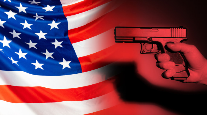 Mercato delle armi in America: pistola impugnata davanti a bandiera americana