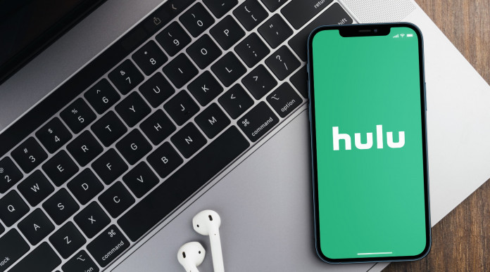 No pubblicità contro le armi, democratici Usa contro Hulu: home di Hulu su smartphone appoggiato a tastiera di computer