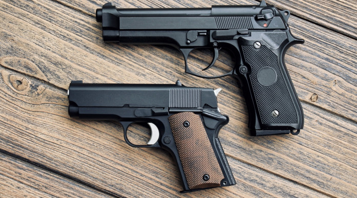Cresce la domanda di pistole microcompatte negli Stati Uniti: due pistole di dimensioni diverse su tavolo di legno