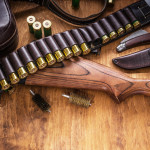 Reati e divieto automatico di porto d’armi: la sentenza Reati e preclusione automatica del porto d’armi: fucile a pompa e cartucce su tavolo di legno