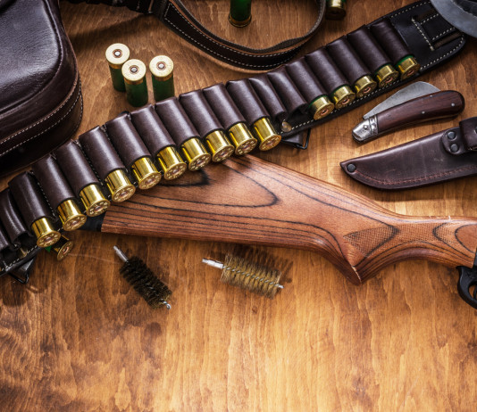 Reati e divieto automatico di porto d’armi: la sentenza Reati e preclusione automatica del porto d’armi: fucile a pompa e cartucce su tavolo di legno