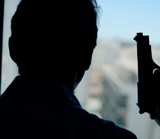 Licenza per uso sportivo e difesa personale: la sentenza Licenza per uso sportivo e difesa personale: uomo davanti alla finestra, di spalle, con pistola in mano