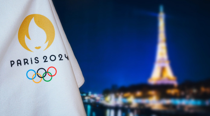 Carte olimpiche per le specialità di tiro: bandiera Parigi 2024 davanti alla Torre Eiffel di notte