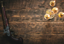 Custodia di armi antiche: la sentenza della Cassazione Custodia di armi antiche: pistola su tavolo di legno accanto a lampada antica