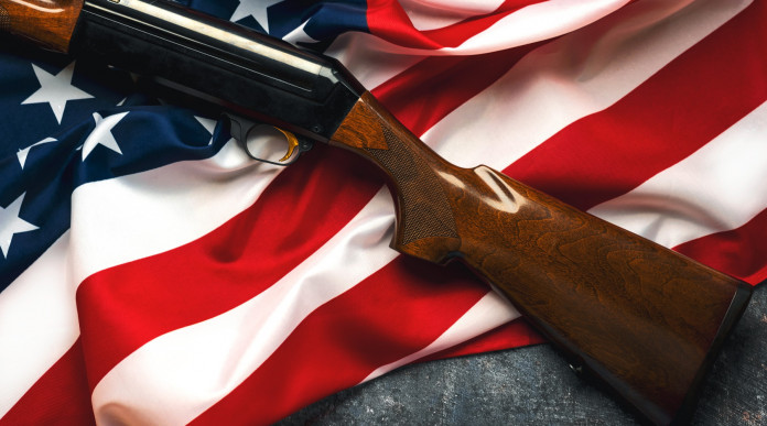 Vendita di armi in America: fucile con calcio in legno su bandiera americana