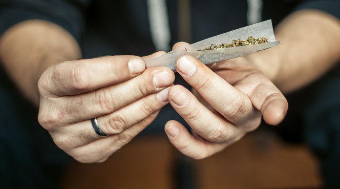 Assunzione occasionale di stupefacenti e porto d’armi: mani di uomo preparano spinello con marijuana
