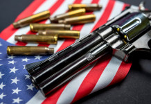 Background check negli Stati Uniti: il dato finale del 2022 Background check negli Stati Uniti: revolver a doppia canna con bandiera americana e munizioni