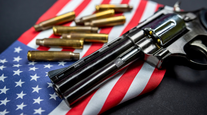 Background check negli Stati Uniti: revolver a doppia canna con bandiera americana e munizioni