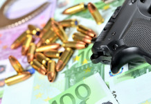 Valore economico del settore armiero in Italia: lo studio Valore economico del settore armiero in Italia: pistola con munizioni e banconote in euro