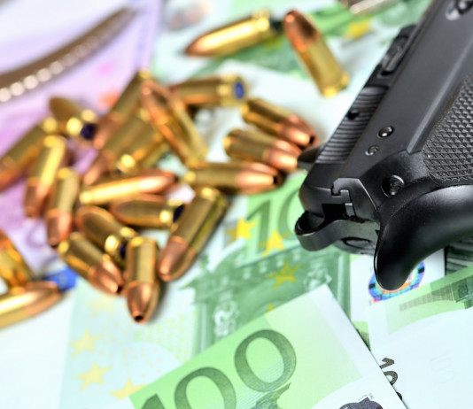 Valore economico del settore armiero in Italia: lo studio Valore economico del settore armiero in Italia: pistola con munizioni e banconote in euro