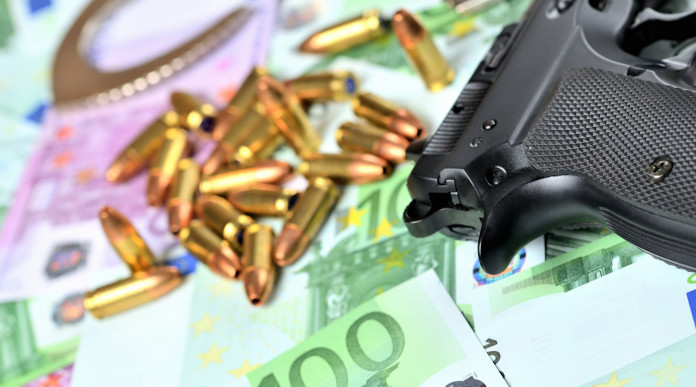 Valore economico del settore armiero in Italia: pistola con munizioni e banconote in euro
