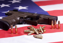 Background check in America: i dati del primo trimestre Background check in America: pistola con munizioni su bandiera americana