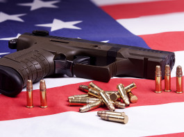 Background check in America: i dati del primo trimestre Background check in America: pistola con munizioni su bandiera americana