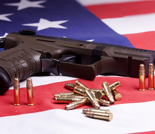 Background check in America: i dati del primo trimestre Background check in America: pistola con munizioni su bandiera americana
