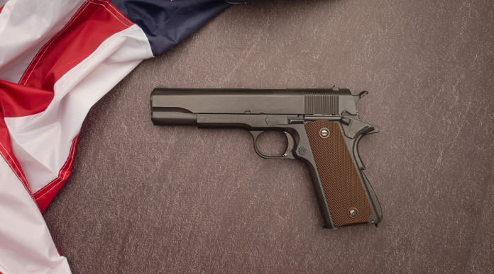 Mercato delle armi in America: pistola circondata da bandiera americana