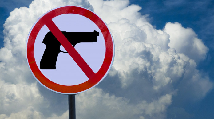 Quanto dura la preclusione alla detenzione di armi: cartello con segnale di pistola vietata, davanti a cielo con nuvole