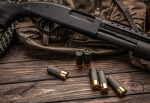 Porto d’armi per finalità diverse da quelle indicate: la sentenza Porto d’armi per finalità diverse da quelle indicate: fucile a pompa su tavolo di legno con cartucce