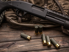 Porto d’armi per finalità diverse da quelle indicate: la sentenza Porto d’armi per finalità diverse da quelle indicate: fucile a pompa su tavolo di legno con cartucce